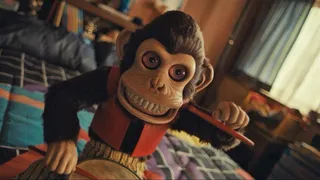 A creepy looking toy monkey sits on a bed holding an instrument