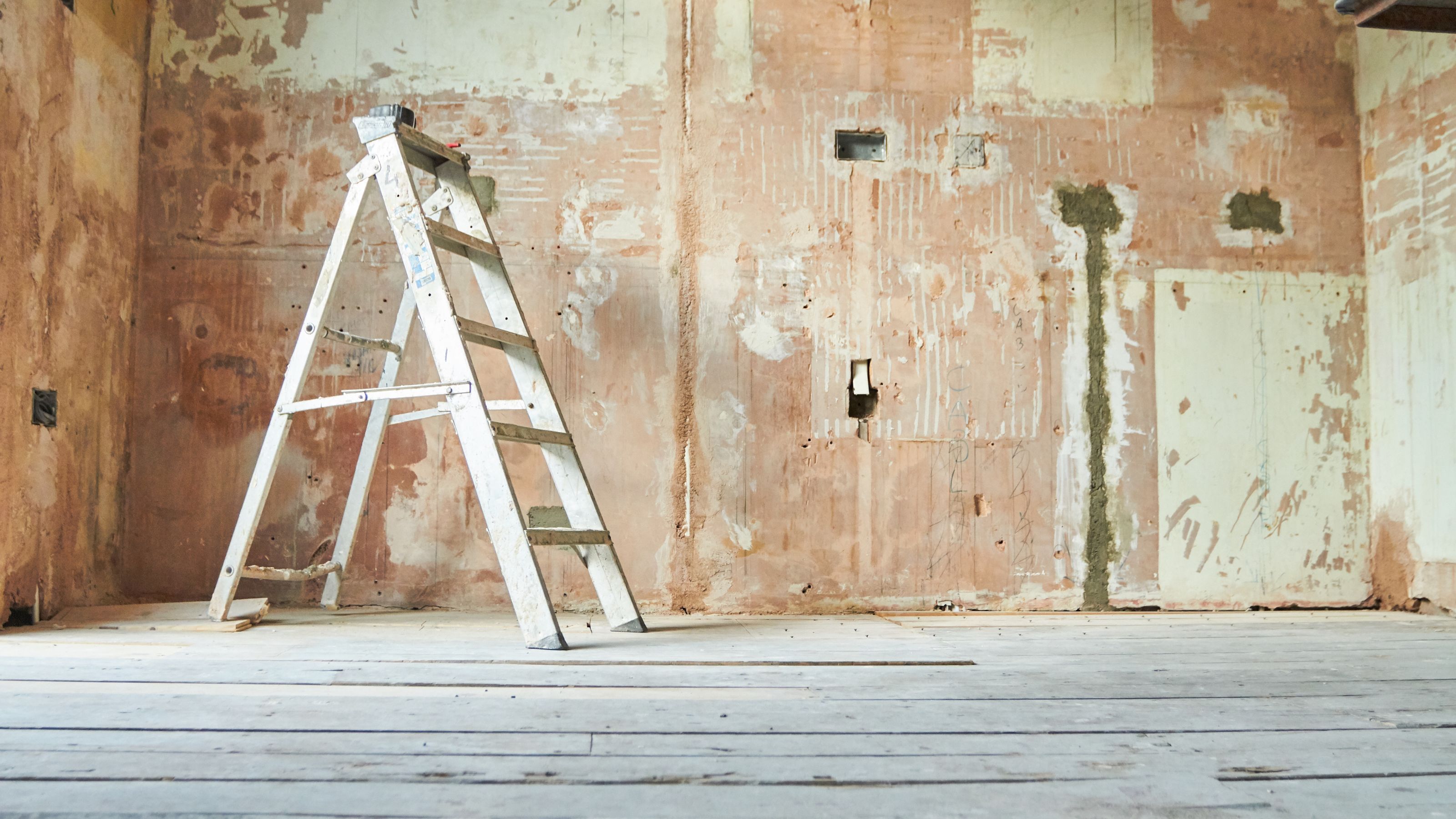 Renovating a room, with stripped walls, bare floorboards and a ladder