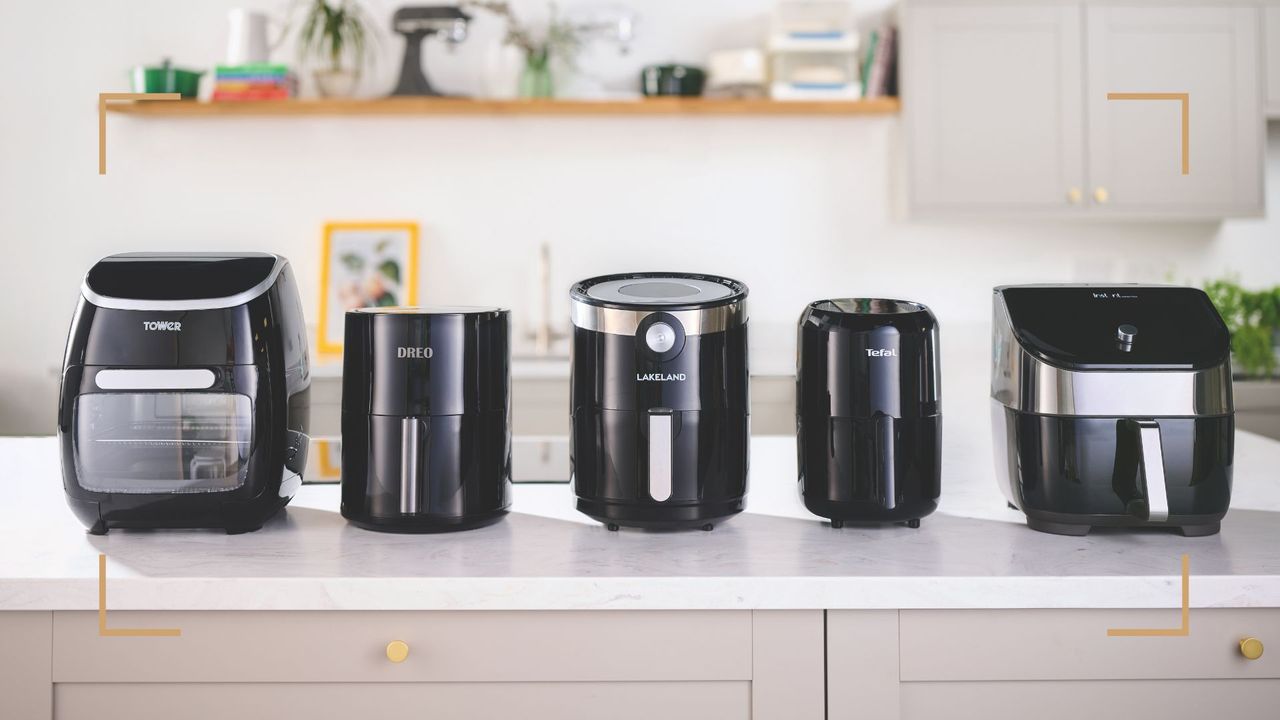 Five black air fryer models lined up along a white marble kitchen counter