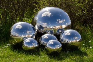 mirrored metal spheres used as a focal point in a garden space