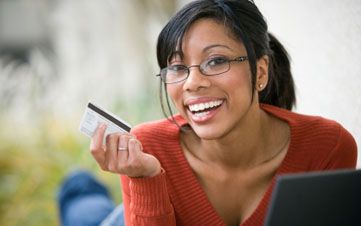 Smiling African American woman shopping online with credit card and laptop 