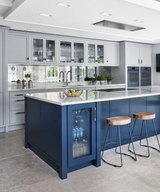 A backsplash ideas for kitchen with mirrored material and blue island