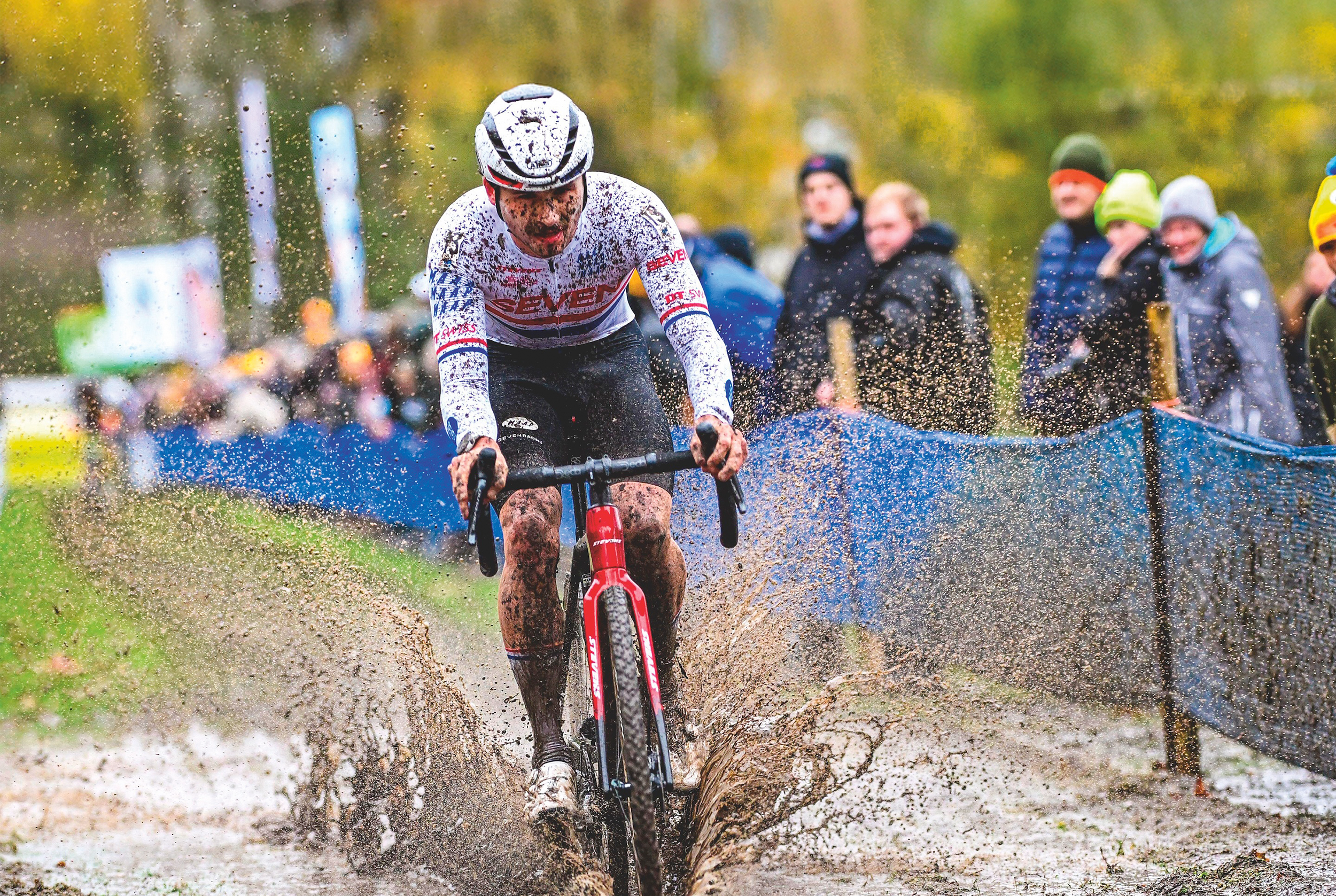 Cameron Mason plows through a muddy puddle at a cyclo-cross race