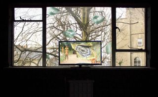 A window with pale green neck cushion window stickers, and a television screen displaying a tribal scene