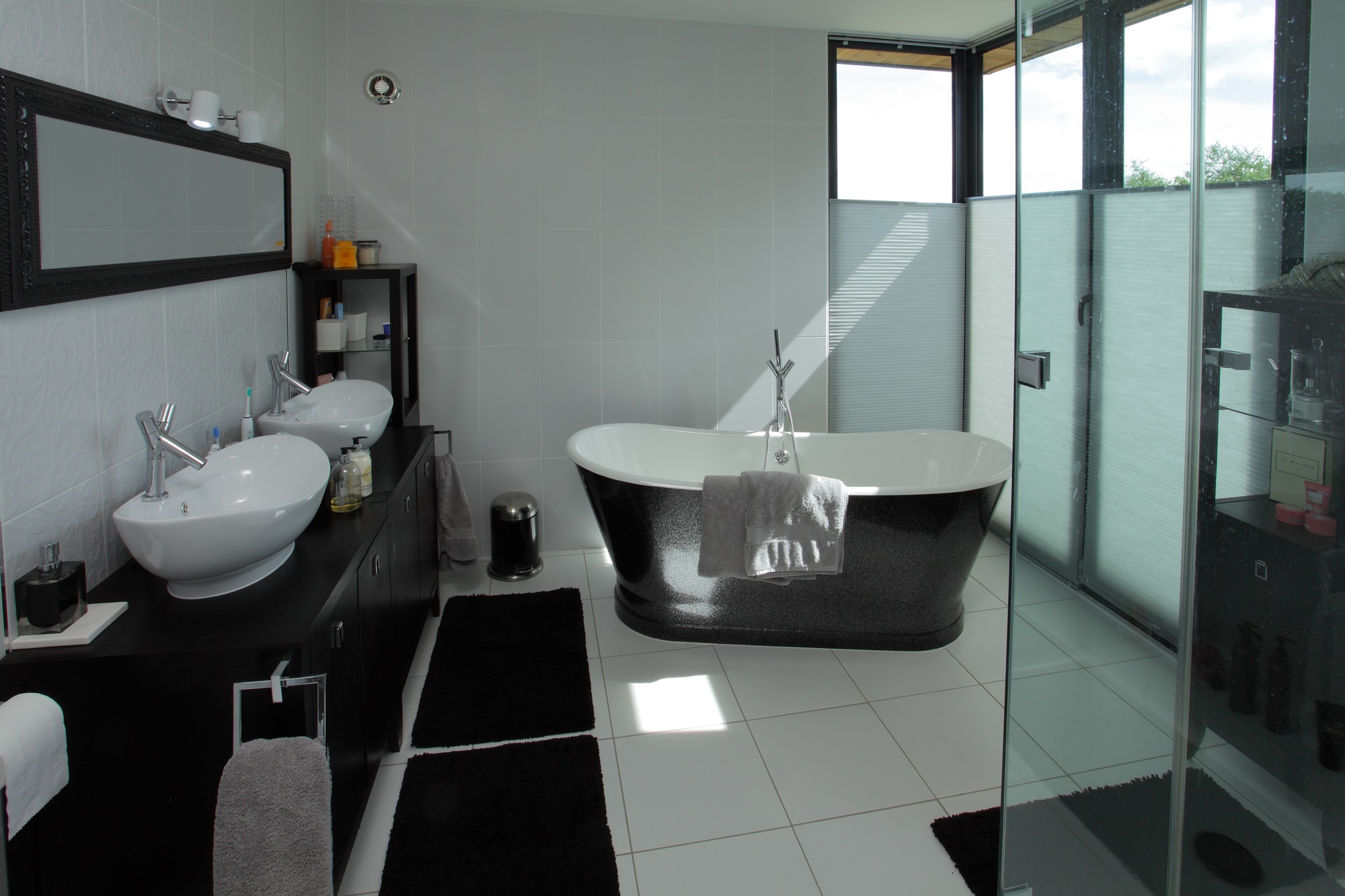 The bathroom with a large bathtub, double sinks and shower with glass surroundinside the grade listed house
