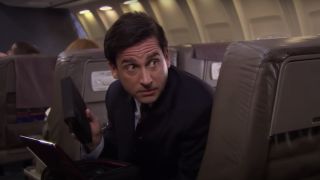 Michael Scott looking behind his plane seat in The Office