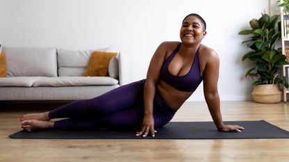 Woman lying on her side on a yoga mat smiling at the viewer