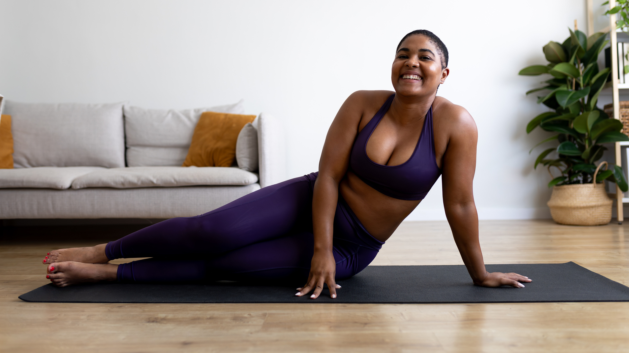 Woman lying on her side on a yoga mat smiling at the viewer