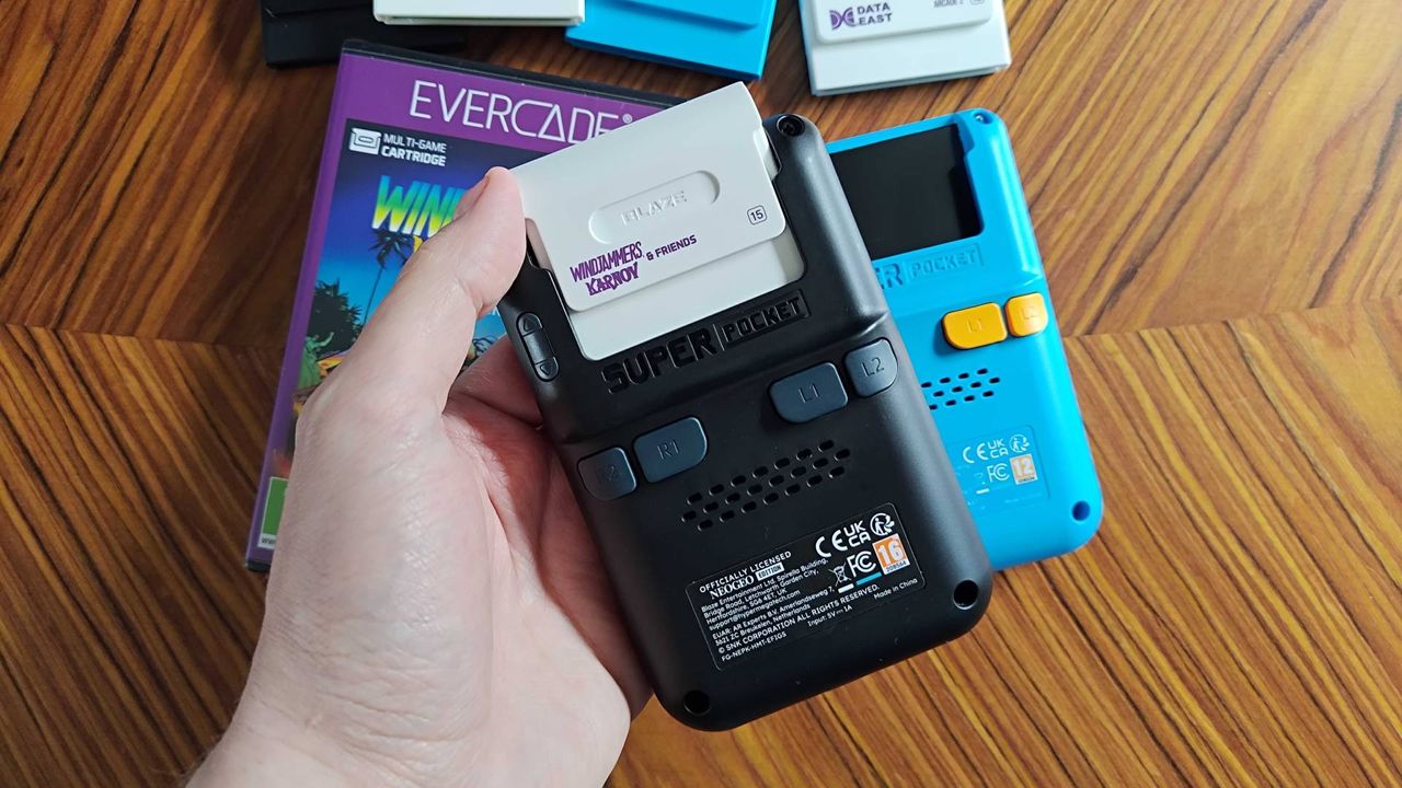 Back of Neo Geo Super Pocket with hand inserting white cartridge.