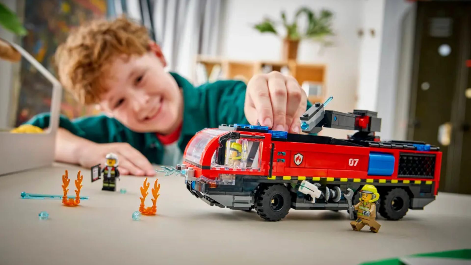 A child plays with the Lego Airport Fire Truck on a table