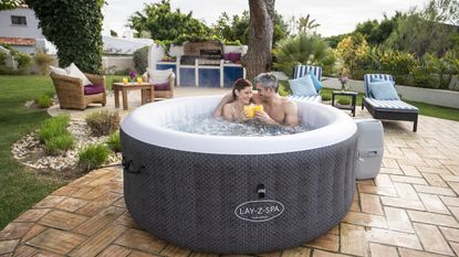 how to drain a hot tub - couple in hot tub on patio