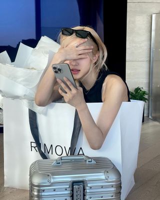 Woman sitting with Rimowa branded bag