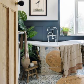 blue patterned floor tiling in bathroom with copper bath and plants