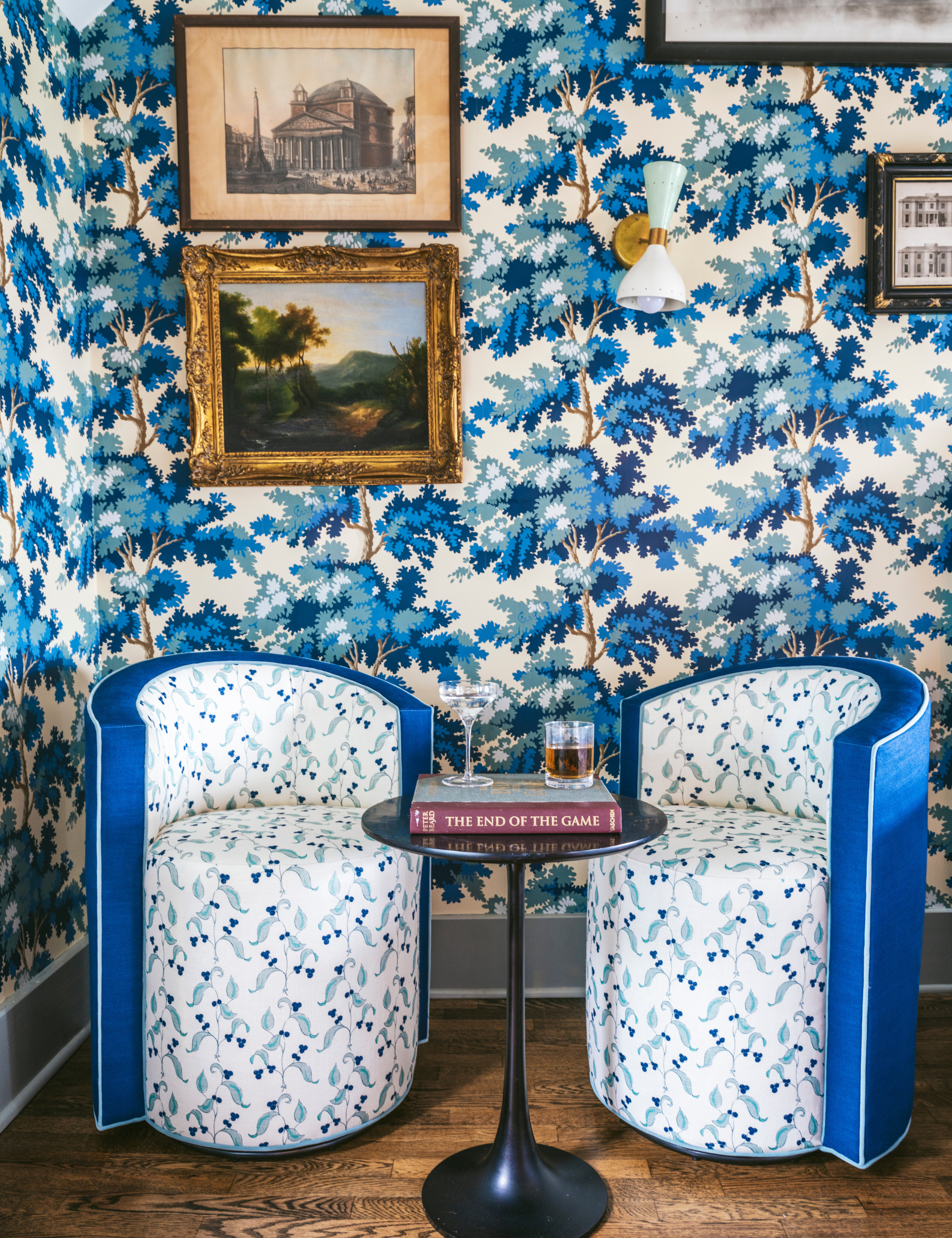 Pattern-drenched seating vignette featuring barrel-style swivel chairs and a black accent table toped with a book and two cocktails