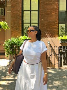 Aysha Sow wearing a white T-shirt and white skirt with a brown tote bag