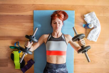 Young fitness woman doing exercise with dumbbells at home