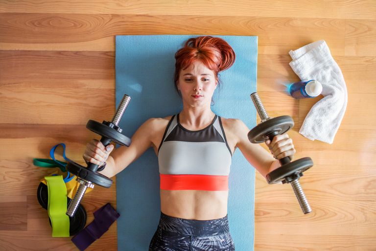 Young fitness woman doing exercise with dumbbells at home