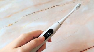 Woman's hand holding Oclean X Pro Elite electric toothbrush
