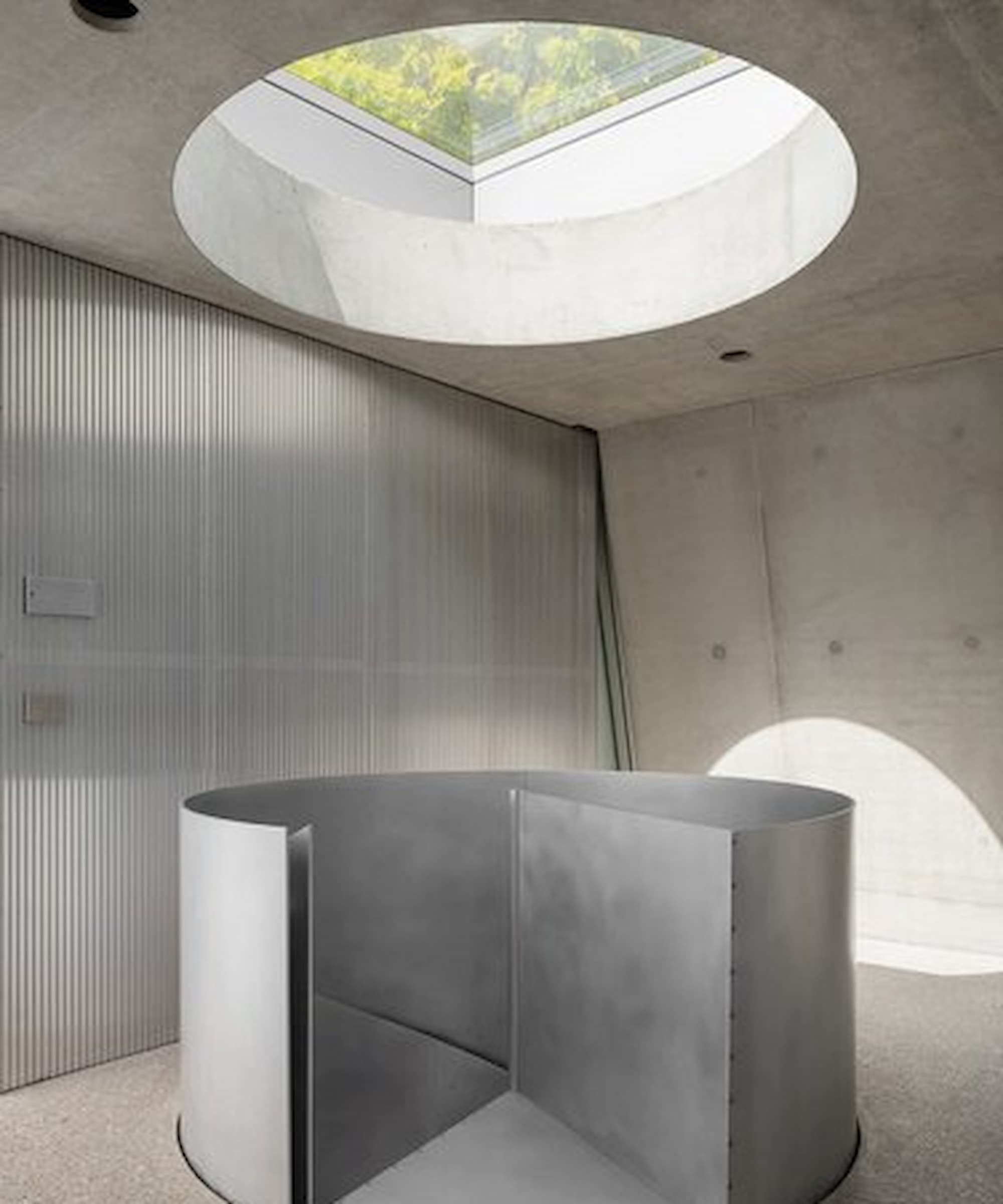 The top of a curved, metal staircase with a rooflight