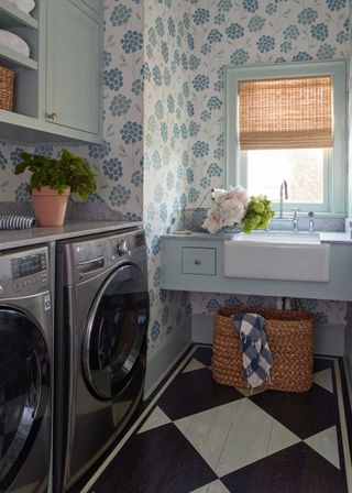 small laundry room which black and white painted flooring and stainless steel appliances and blue floral wallpaper