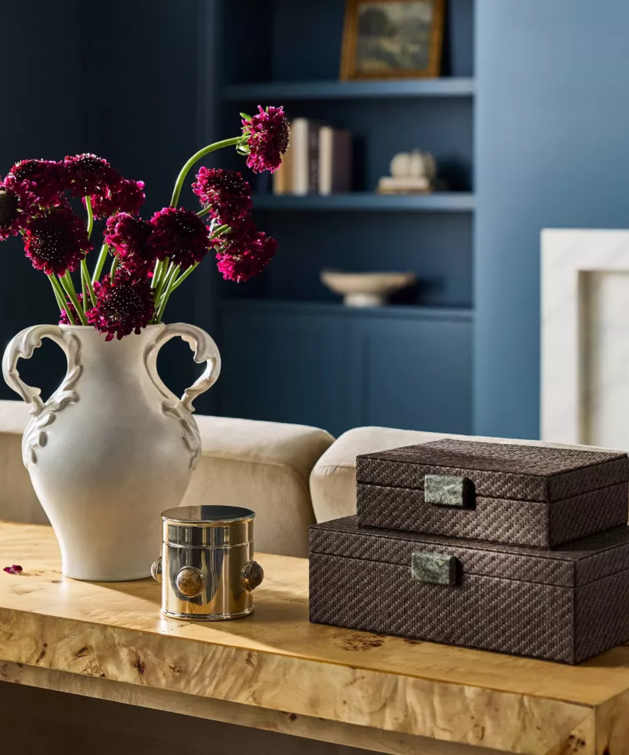 a tabletop scene with boxes, a canister, and a vase with flowers