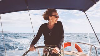 Woman steering sail boat looking out at the waves