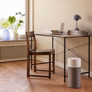 A cylindrical air purifer by a desk in a home office