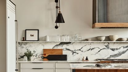 a kitchen with bold veined marble countertops and a silvery cooker hood