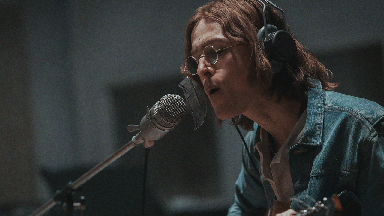 Harris Dickinson with long hair and glasses, as John Lennon