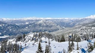 Scenic view of snow covered mountains and blue sky taken from the top of Blackcomb Mountain in British Columbia