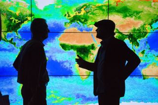 Actor Leonardo DiCaprio (right) speaks with Piers Sellers in front of a wall display showing biosphere data at NASA’s Goddard Space Flight Center in Maryland in April 2016.