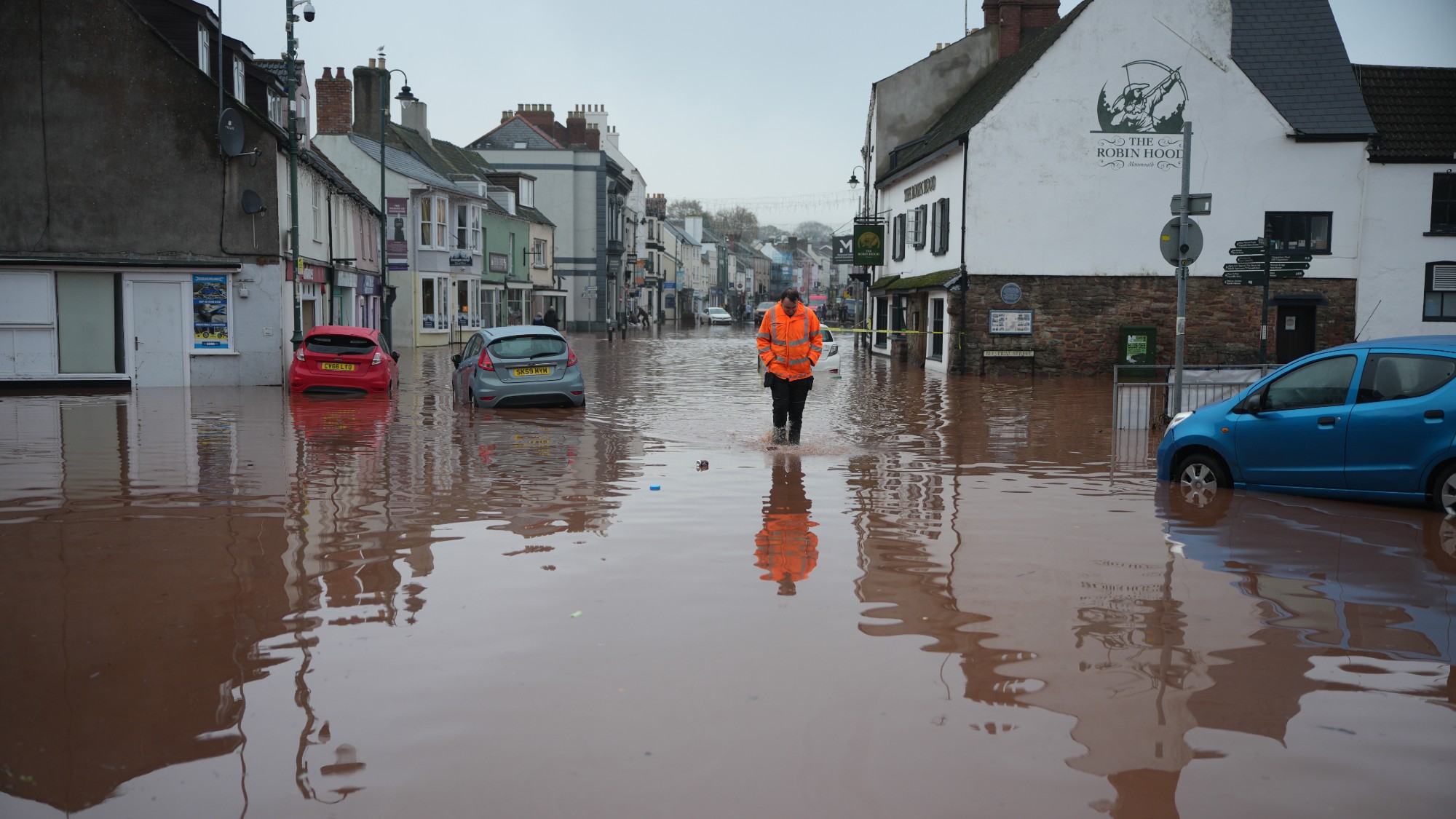 A man wades through a flooded street in Monmouth after Storm Claudia
