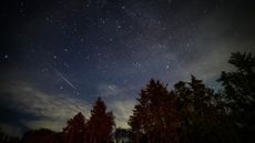 A streak of white light is seen against a dark night sky