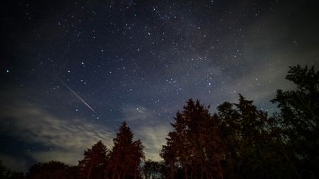 A streak of white light is seen against a dark night sky