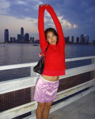 Woman wearing a red sweater with a pink satin skirt.