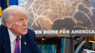A man sits in front of a screen with a yellow shape on it