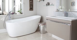 White and grey bathroom with freestanding bath on marble stone flooring