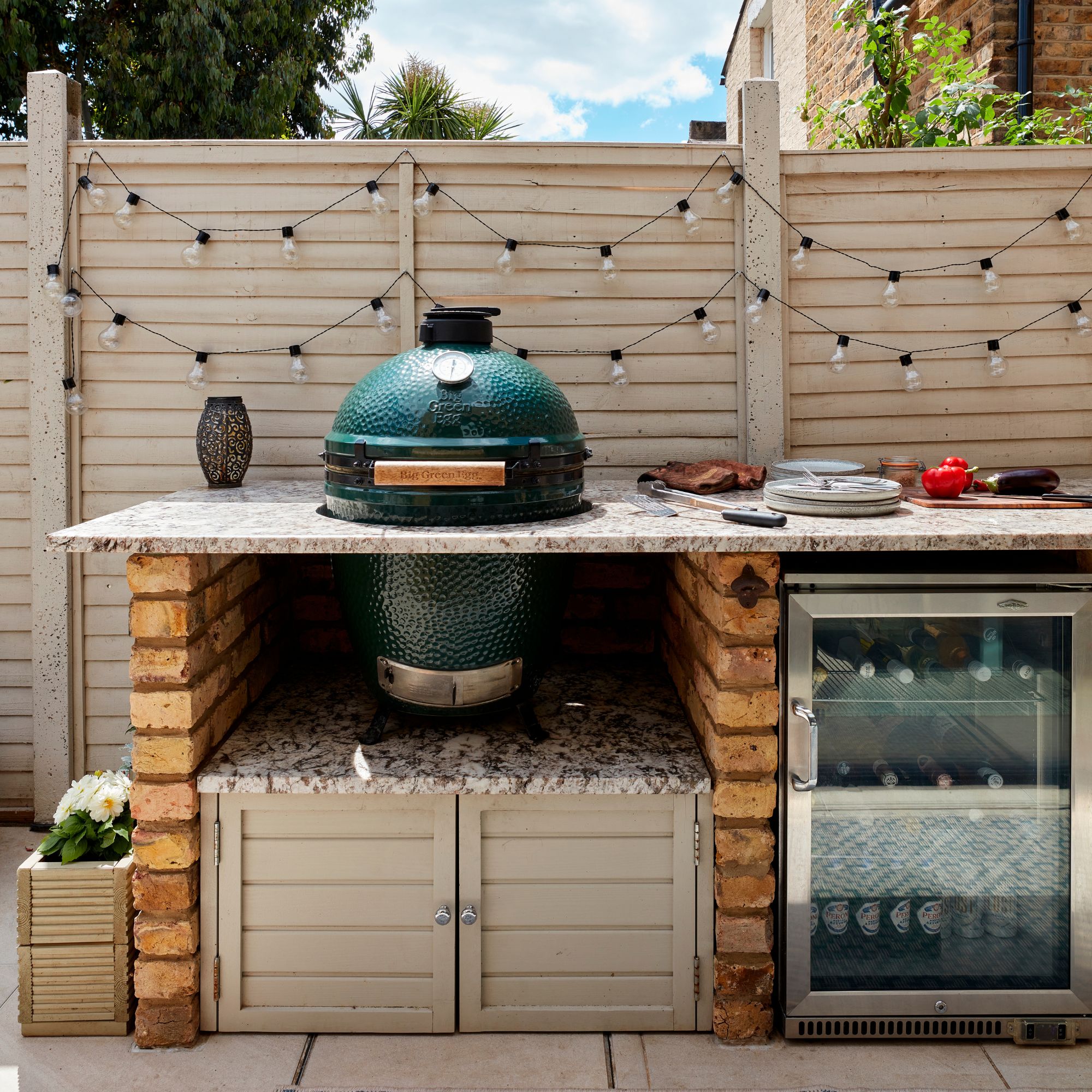Outdoor kitchen area with a big green egg BBQ on top of a kitchen unit