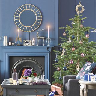 A blue painted living room with a matching fireplace and a decorated Christmas tree next to it