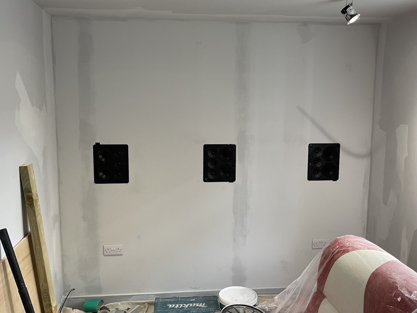 An image of a stud wall being constructed for three in-wall speakers to be embedded