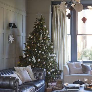 christmas tree in neutral living room with paper decorations hanging from ceiling