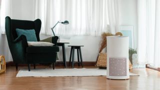 An air purifier in a living room next to a chair, lamp and side table