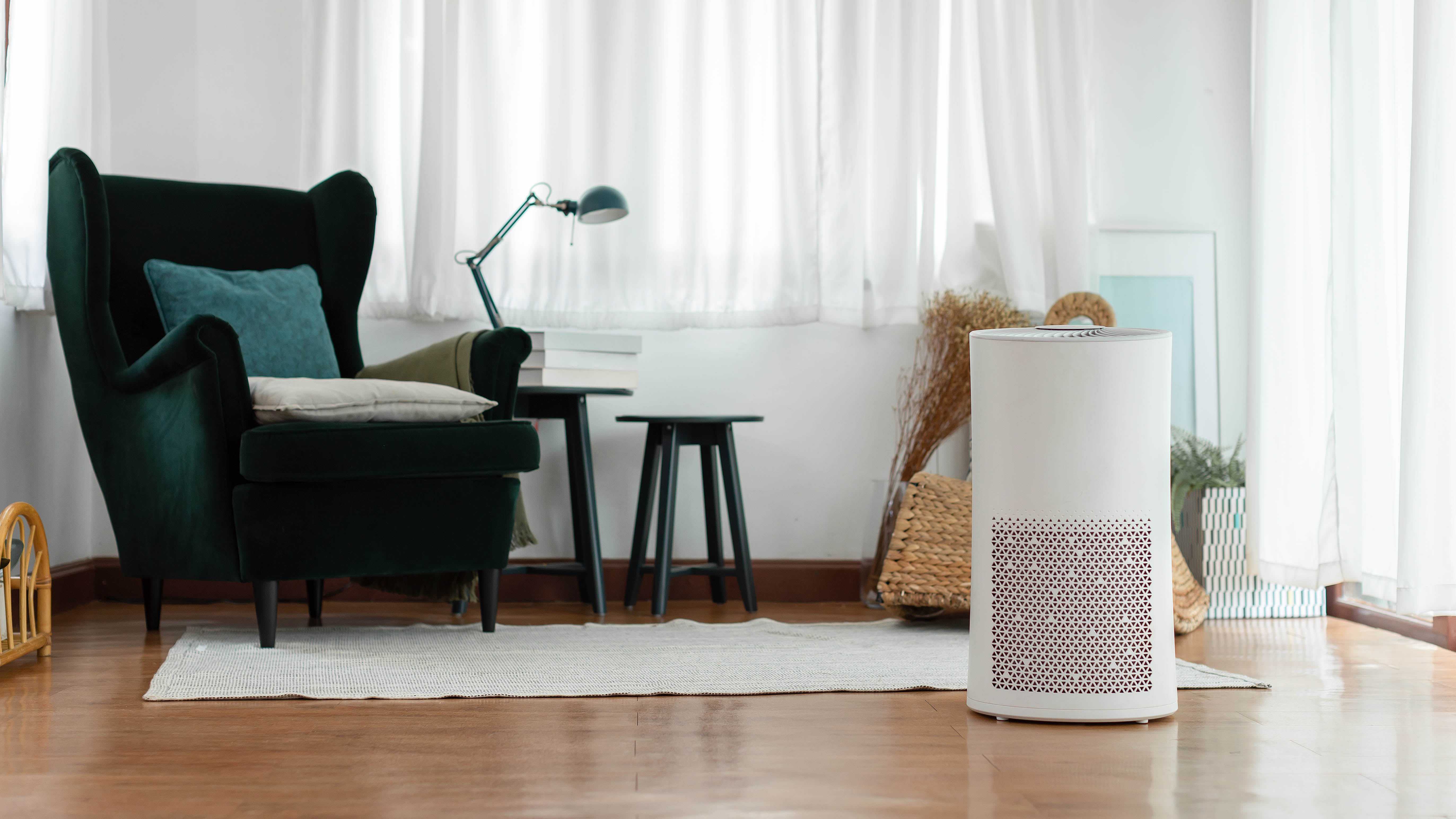 An air purifier in a living room next to a chair, lamp and side table