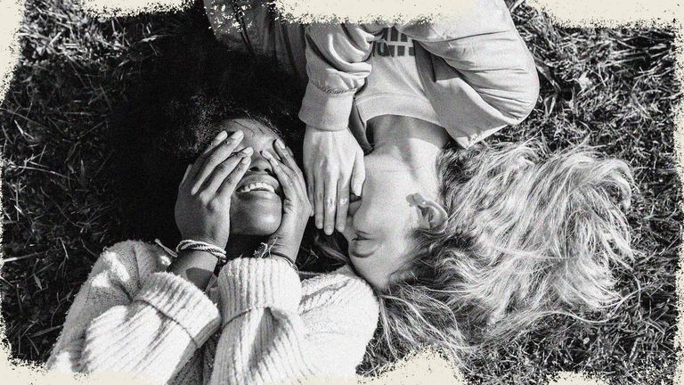 Two best friends telling secrets lying in the grass