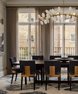 A large dining room with high ceilings, a sculptural light fixture, and floor to ceiling windows