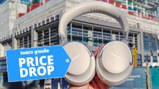 Bose QuietComfort Ultra Headphones being held up in front of urban building with price drop badge