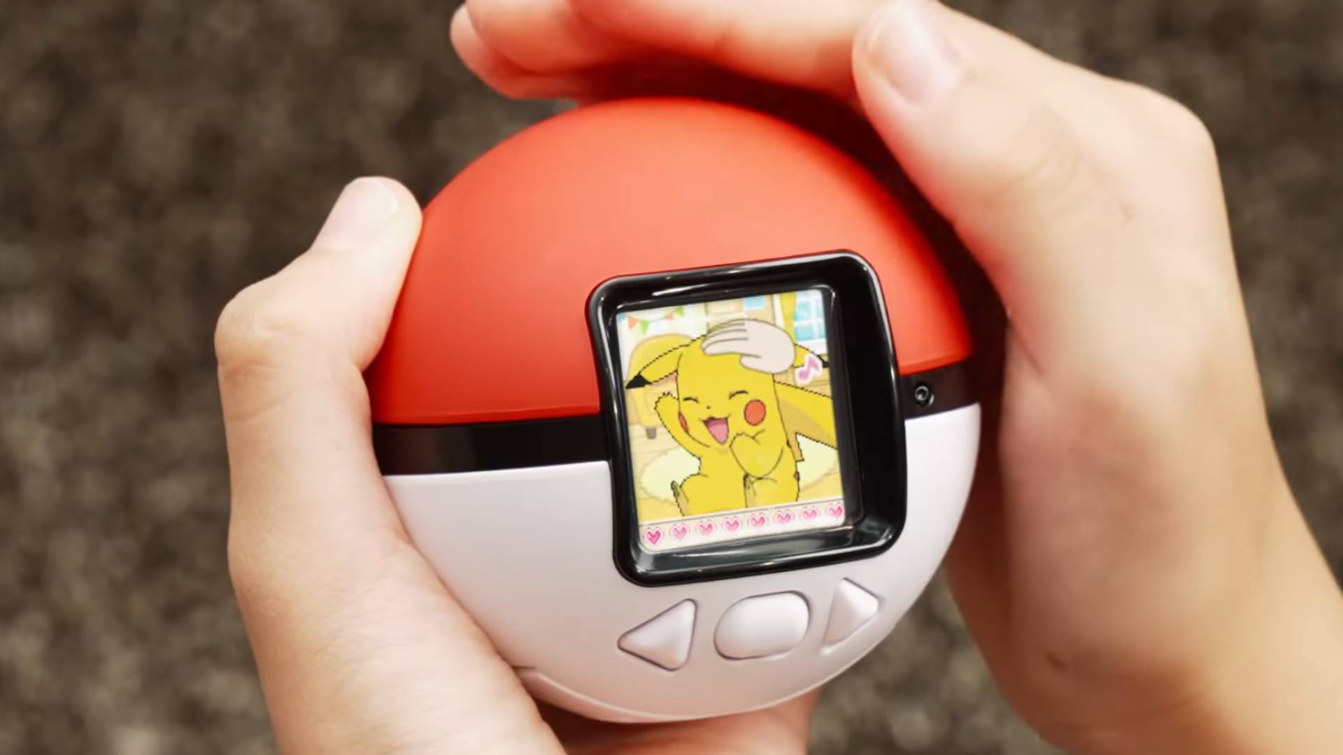Image of a hand petting a Pokeball with Pikachu showing on a display screen.