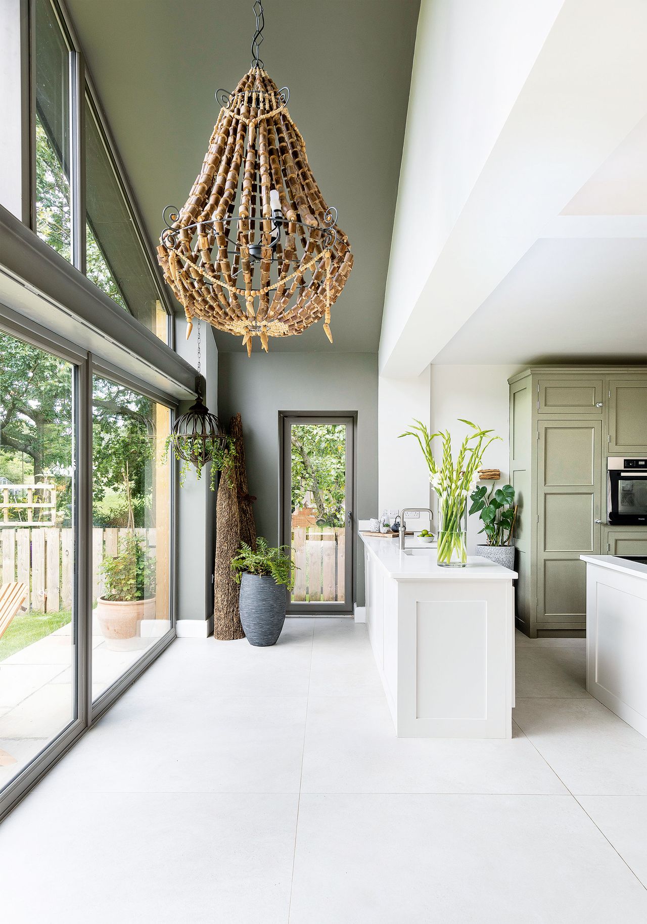 kitchen wall with full height gable end glass window wall and pale gray green painted wall and ceiling kitchen sink set in white worktop