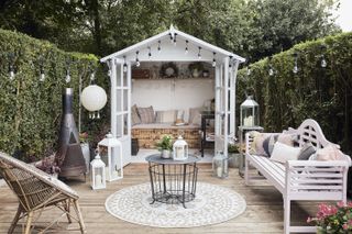 pretty she shed opening onto an outdoor seating area with cushions, a coffee table, and festoon lights