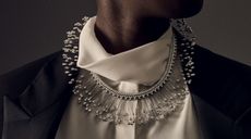 A large neckless that sits over blouse and around the neck. The inner section is stone-encrusted - possible diamonds. Sticking out are a continuous flow of sticks with a stone on the end. 